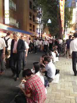 350ほおずき市06歩道に座って食べる人々.jpg